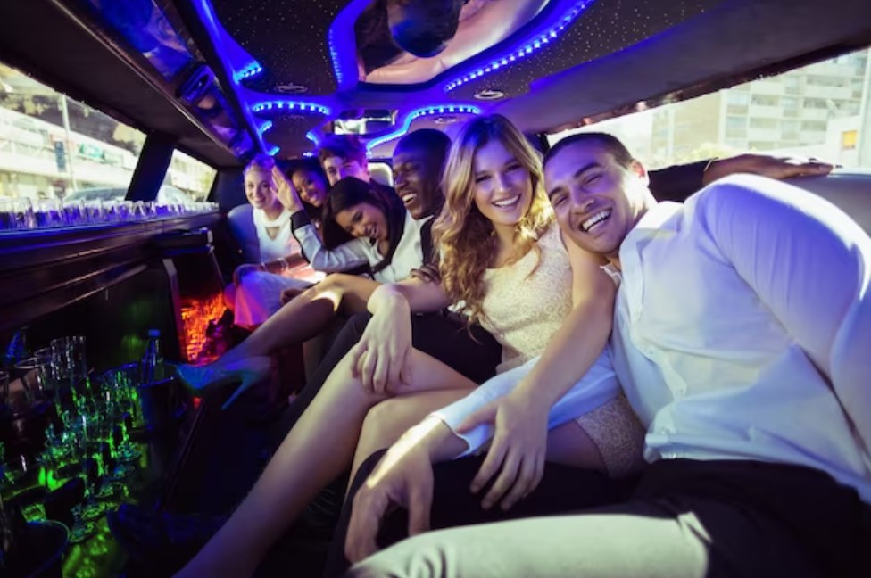 a company of people sitting in a limo with ambient lighting and laughing in the camera