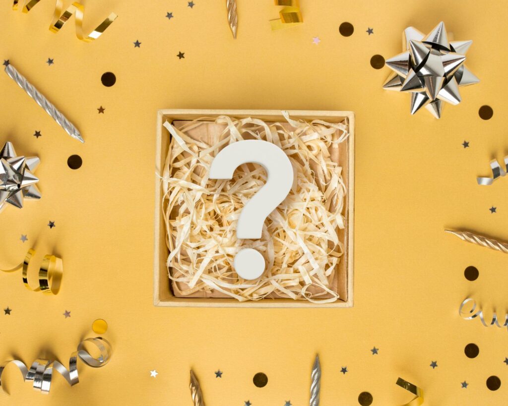 a mystery box with a white question mark inside of it and decor accessories laying around on a yellow background