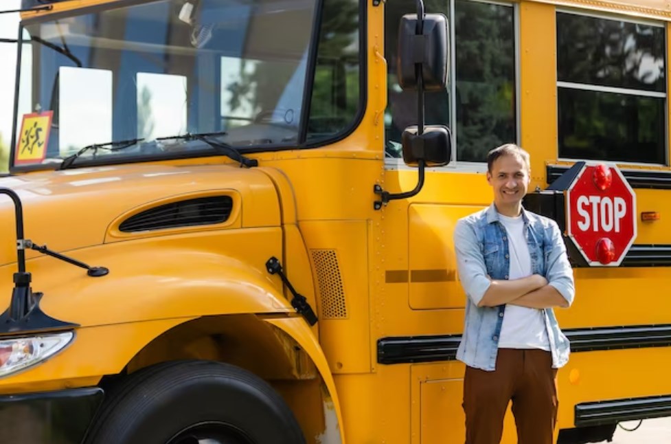 a man standing near a yellow school bus with a stop sign on the right