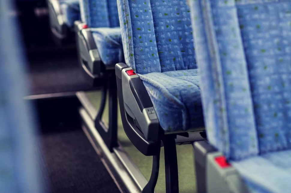 a blue seats in a public bus and stairs behind